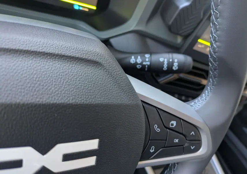Gros plan sur le volant du Dacia Bigster Hybrid 155 Extreme, montrant les commandes multifonctions à droite.