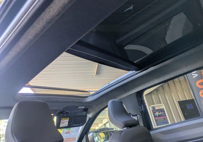 Vue intérieure du toit ouvrant panoramique électrique du Dacia Bigster Hybrid 155 Extreme avec sièges avant noirs.