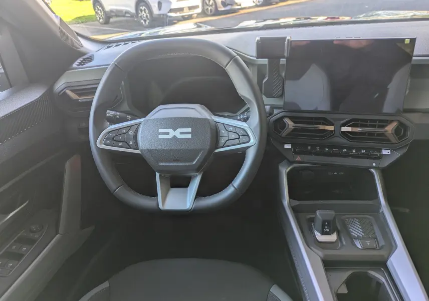 Vue intérieure centrée sur le volant et la console centrale du Dacia Bigster Hybrid 155, avec écran tactile et commandes modernes.