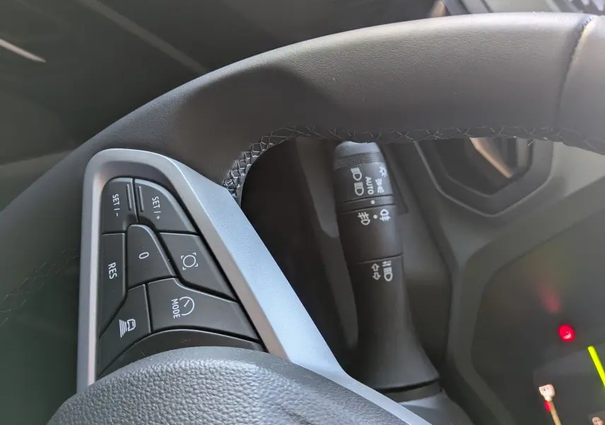 Gros plan sur le volant côté gauche du Dacia Bigster Hybrid 155, montrant les commandes intégrées et la commande des phares.