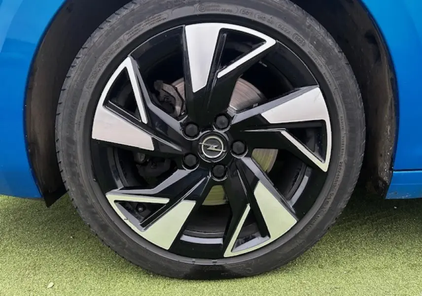 Gros plan sur la jante alliage 17 pouces noir et argent d'une Opel Astra bleu clair, côté arrière droit.