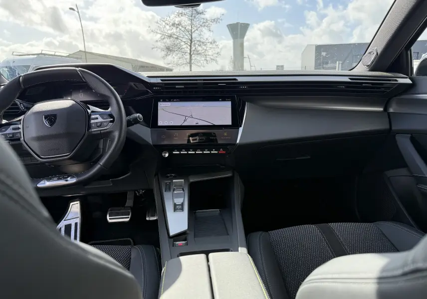 Intérieur moderne du Peugeot 308 SW BlueHDi 130 GT 2024, vue du poste de conduite avec écran tactile central et volant compact.