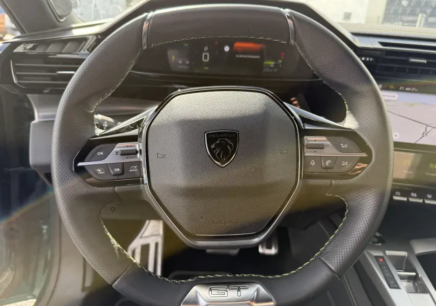 Volant en cuir noir avec logo Peugeot et badge GT au centre, intérieur moderne du Peugeot 308 SW Bleu Avatar 2024.