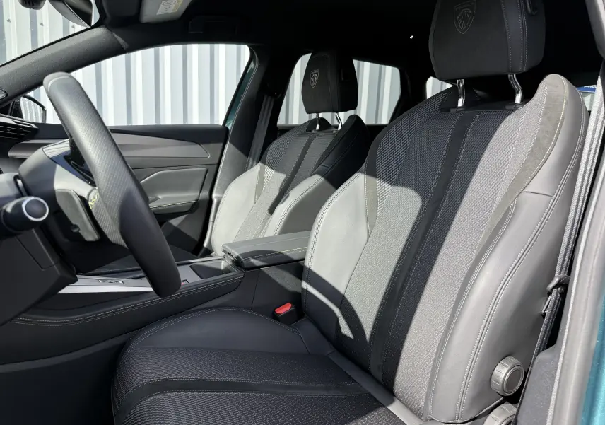 Intérieur avant droit du Peugeot 308 SW Bleu Avartar 2024, sièges en cuir et tissu avec logo Peugeot brodé sur appuie-tête.