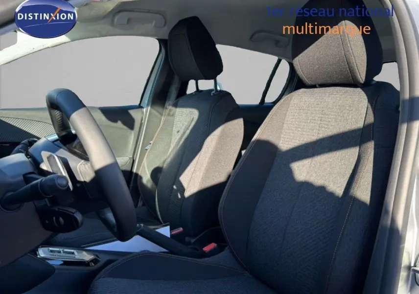 Vue intérieure côté conducteur du Peugeot 208 gris avec sièges tissu gris et volant multifonction.