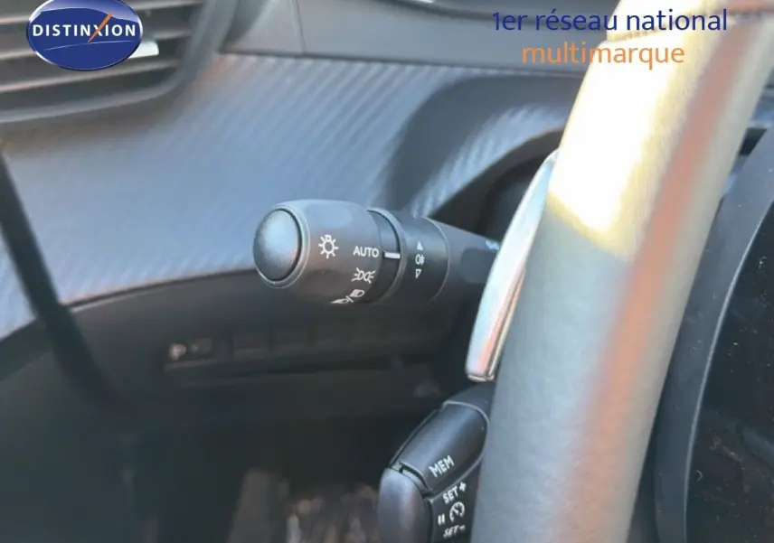 Gros plan sur la commande des phares et régulateur de vitesse derrière le volant d'une Peugeot 208 gris Artense 2025.
