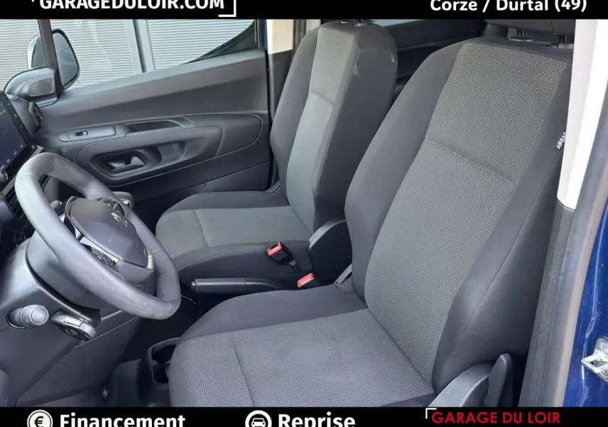 Vue intérieure côté conducteur du Peugeot Rifter bleu 2024, montrant les sièges tissu gris et le volant noir.