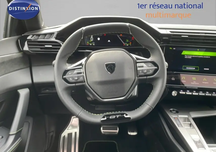Intérieur Peugeot 308 GT 2026, vue centrée sur le volant cuir noir avec surpiqûres vertes et tableau de bord numérique.