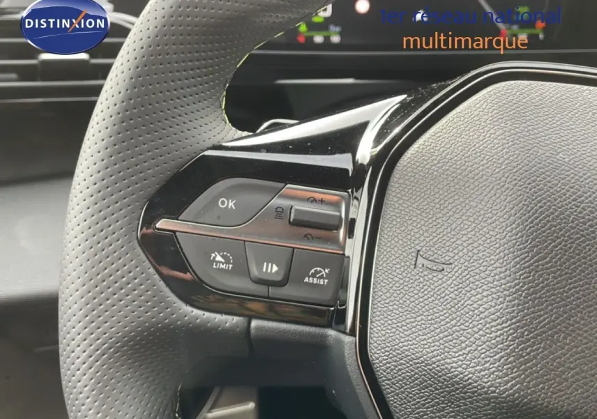 Gros plan sur le volant perforé et les commandes multifonctions à gauche du Peugeot 308 gris Selenium Hybrid 2026.