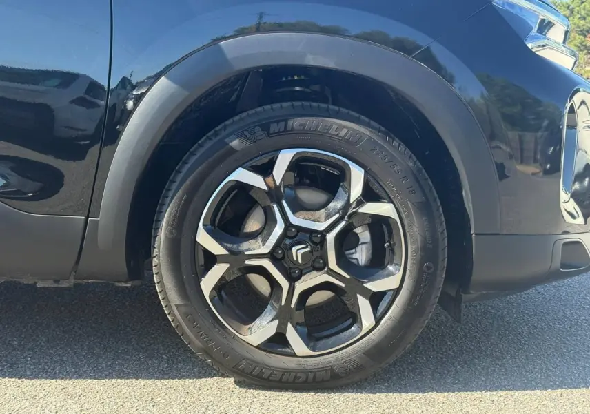 Gros plan sur la roue avant gauche du Citroën C5 Aircross noir Perla Nera avec jante alu bicolore et pneu Michelin.