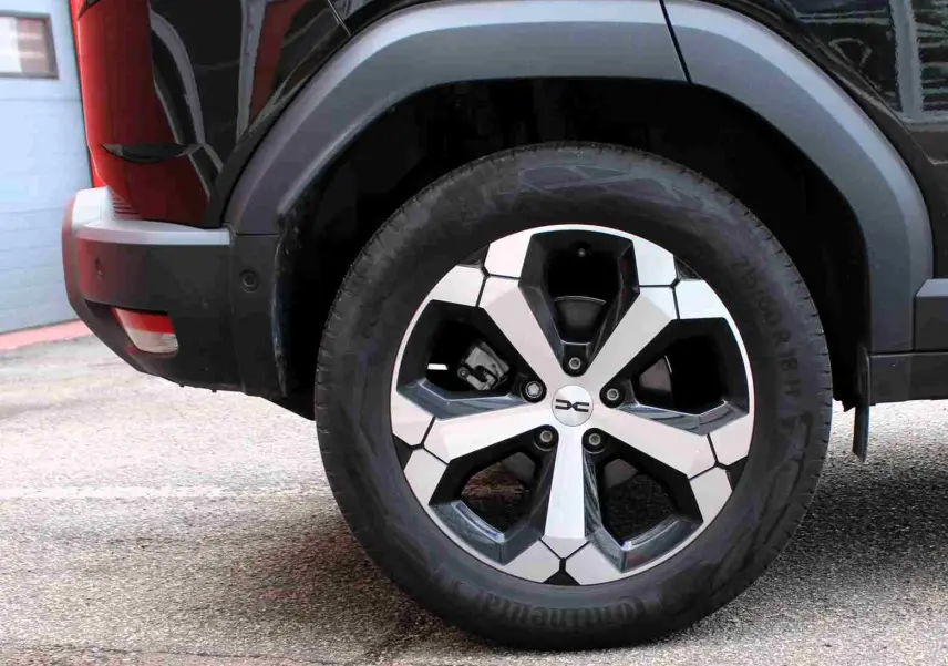 Gros plan sur la roue arrière droite du Dacia Duster 2025 noire avec jante alliage 18 pouces diamantée Tagasan.