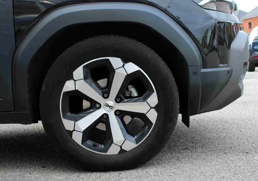 Gros plan sur la roue avant droite du Dacia Duster noir 2025 avec jante alliage diamantée Tagasan.