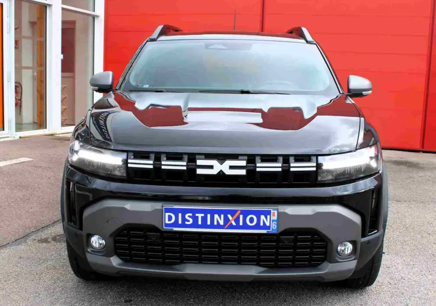 Vue frontale d'un Dacia Duster III noir nacré avec calandre distinctive et plaques d'immatriculation Distinxion.