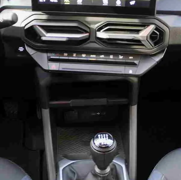 Vue intérieure centrée sur la console centrale et levier de vitesses manuelle du Dacia Duster 2025, sellerie Denim Bleu.