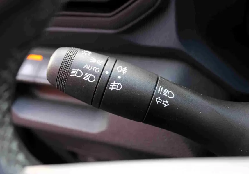 Gros plan sur la commande des feux et clignotants du Dacia Duster III noir, intérieur avec détails en gris acier.