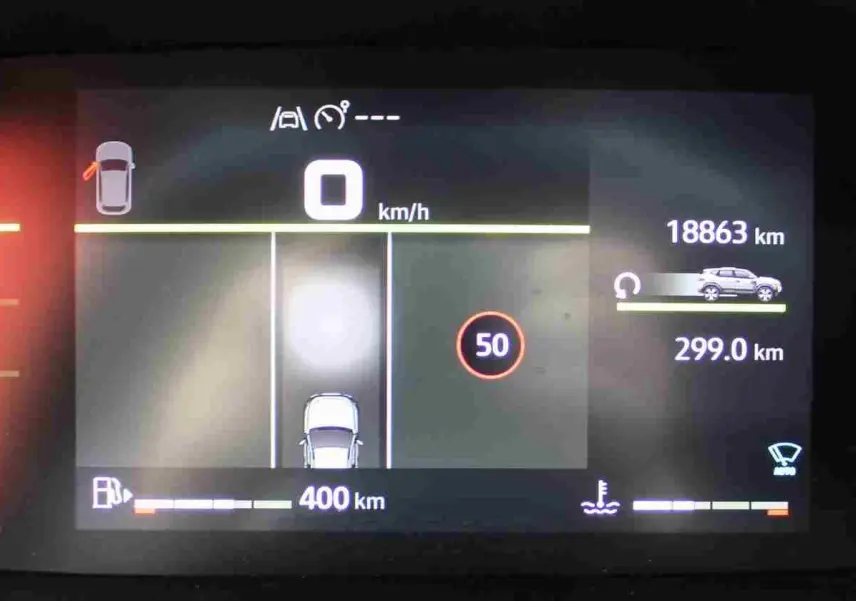 Tableau de bord digital du Dacia Duster 2025 affichant la vitesse, autonomie et alertes, vue de face.