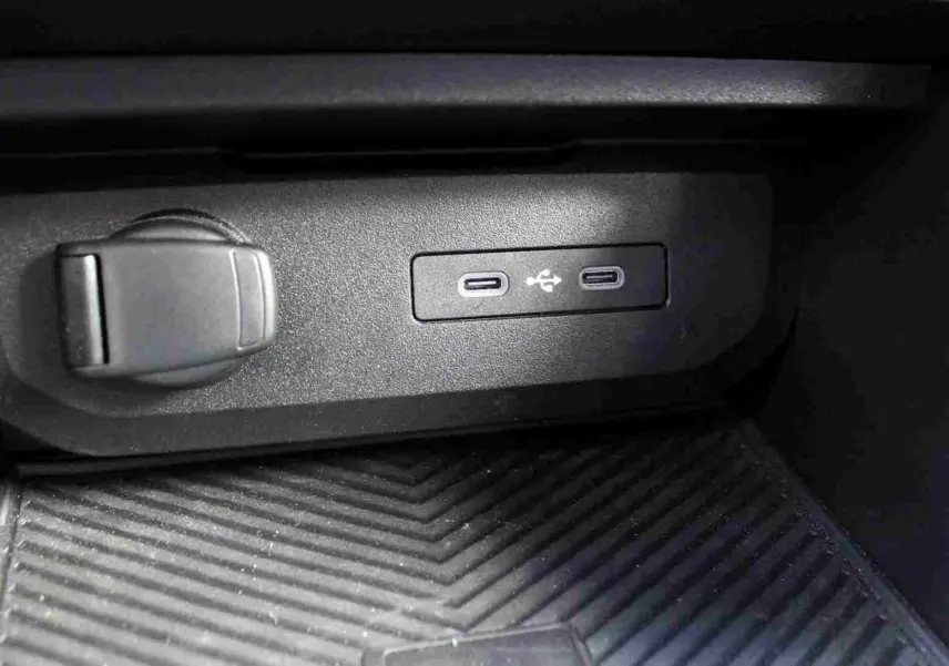 Gros plan sur la console centrale du Dacia Duster III noire, montrant deux prises USB type C et une prise 12V.
