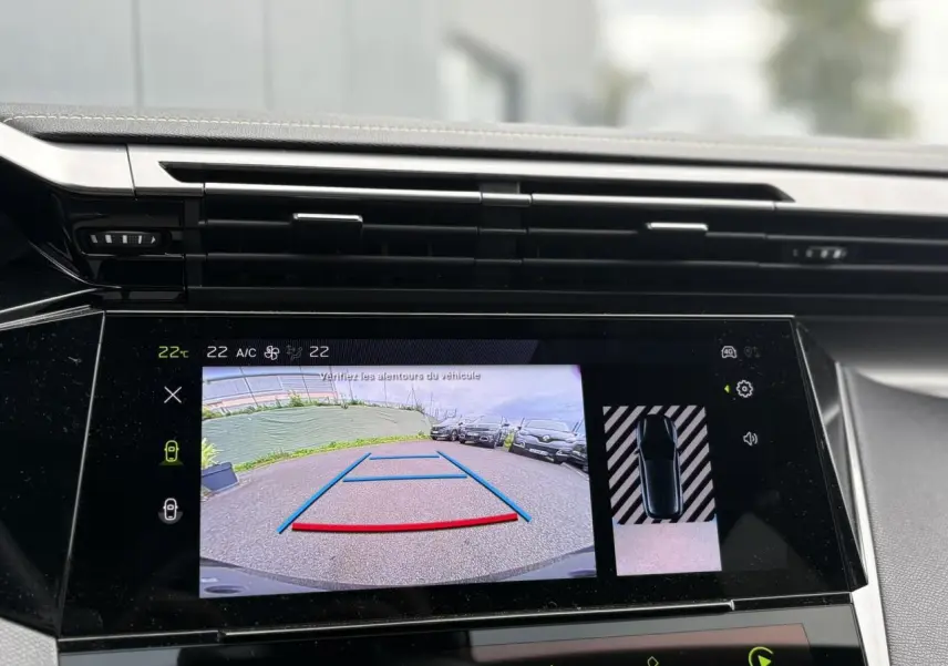 Écran central tactile montrant la caméra de recul et l'aide au stationnement d'une Peugeot 308 blanche Okenite.