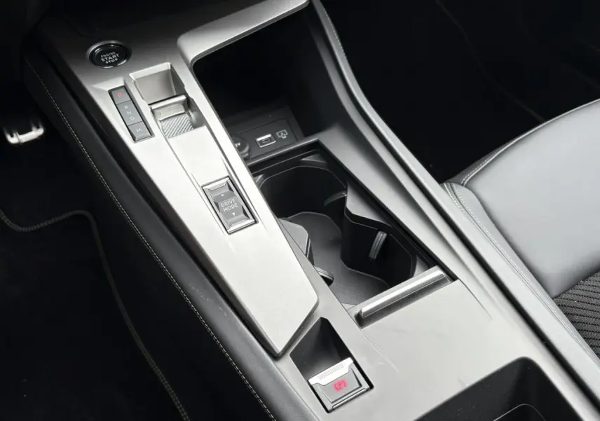 Console centrale de la Peugeot 308 GT 2024 avec levier de vitesses automatique et bouton Drive Mode, sellerie noire.