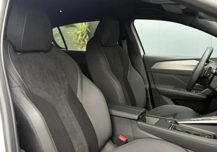 Intérieur de la Peugeot 308 2024, vue côté gauche, sièges avant en sellerie tri matières noire avec surpiqûres blanches.