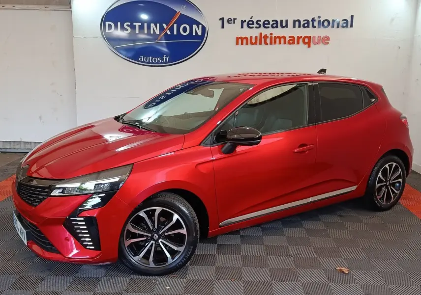 Renault Clio Techno TCe 90 rouge vue de profil côté gauche en intérieur avec jantes alliage et feux LED distinctifs.