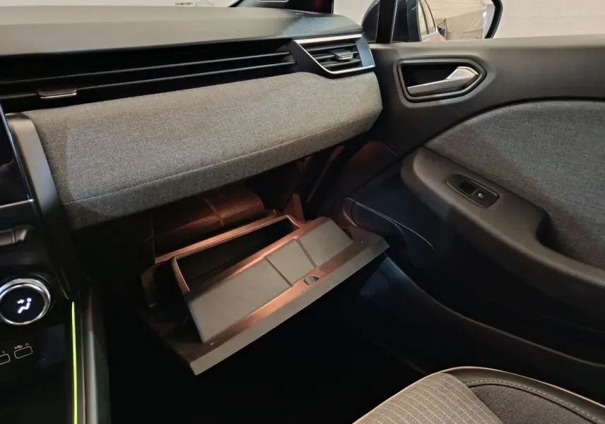 Intérieur côté passager de la Renault Clio Techno TCe 90 2024, boîte à gants ouverte et tissu gris texturé sur la planche de bord.