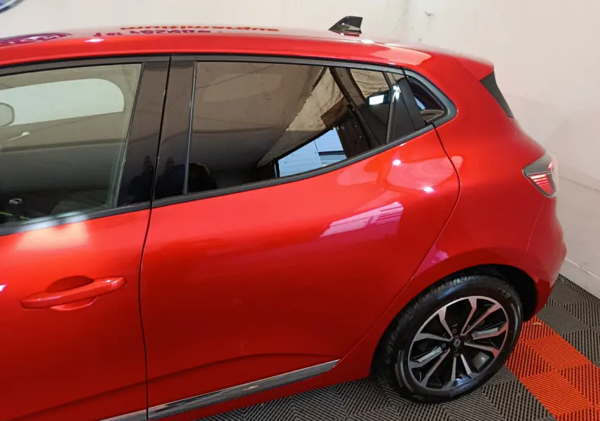 Vue latérale côté gauche d'une Renault Clio rouge 2024 avec jantes alliage et vitres teintées.