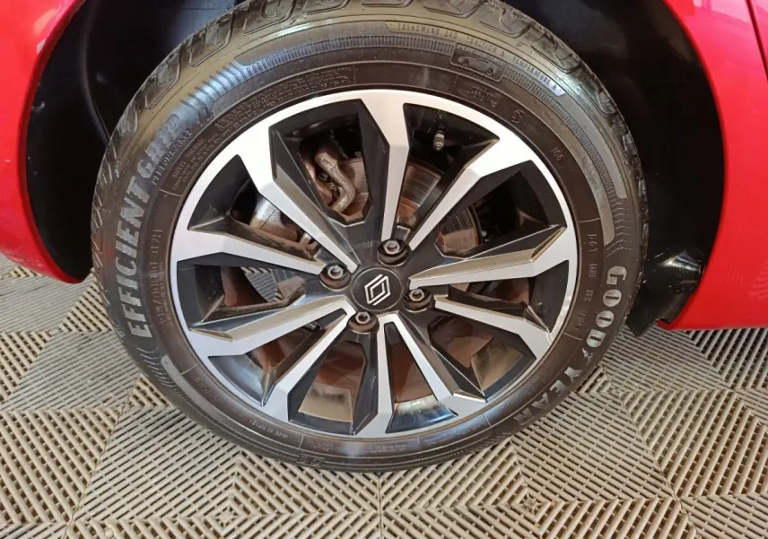 Gros plan sur la roue avant droite d'une Renault Clio rouge 2024 avec jante alliage noire et argentée.