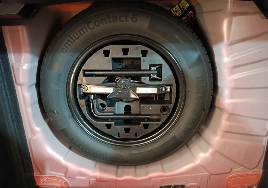 Gros plan sur la roue de secours et les outils de bord dans le coffre rouge d'une Renault Clio Techno TCe 90 2024.