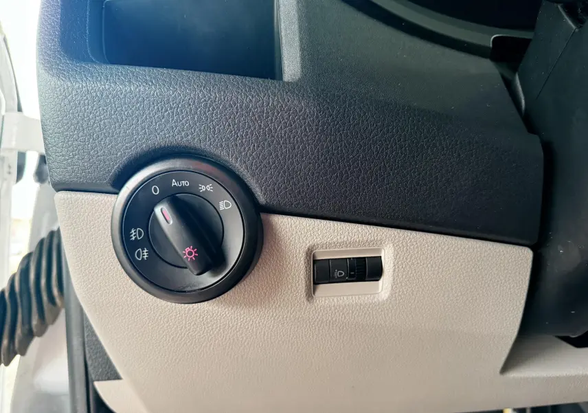 Détail du tableau de bord côté gauche du Volkswagen Transporter blanc 2018, avec commande des phares et réglage de l’éclairage.