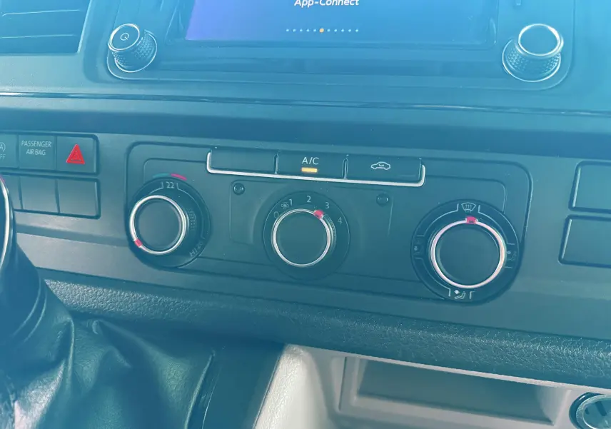 Vue rapprochée du tableau de bord du Volkswagen Transporter blanc 2018, montrant les commandes de climatisation et la console centrale.