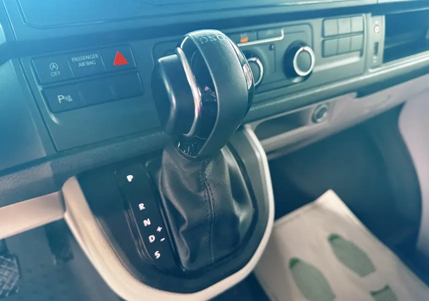 Gros plan sur la commande de boîte automatique DSG du Volkswagen Transporter L1H1 blanc, tableau de bord en arrière-plan.