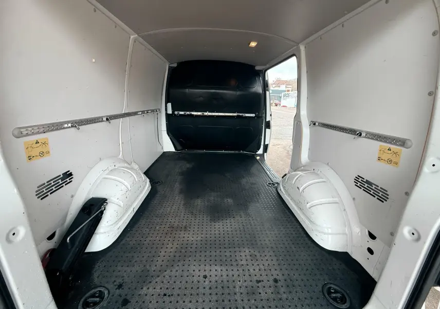 Vue intérieure arrière du Volkswagen Transporter L1H1 blanc de 2018, montrant l’espace de chargement vide avec sol noir antidérapant.