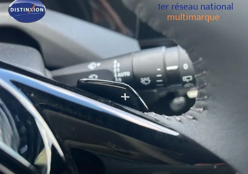 Gros plan sur la palette de changement de vitesse "+" derrière le volant en cuir d'une Peugeot 308 hybride 2024.