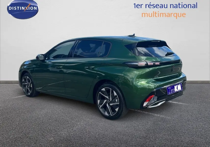 Peugeot 308 vert olivine métal vue 3/4 arrière côté gauche, avec jantes alliage et feux arrière LED distinctifs.