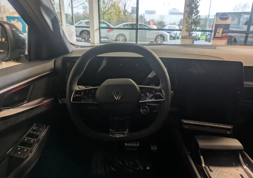 Vue intérieure centrée sur le volant multifonction noir du Renault Austral Ph.2, avec tableau de bord numérique et écran tactile.