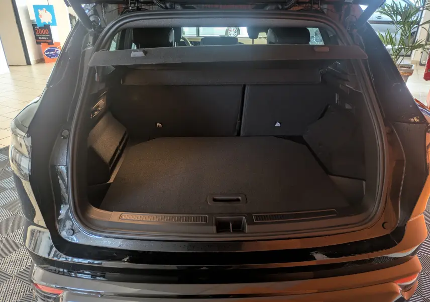Coffre ouvert vu de l'arrière d'un Renault Austral noir, montrant un espace de chargement spacieux et propre.