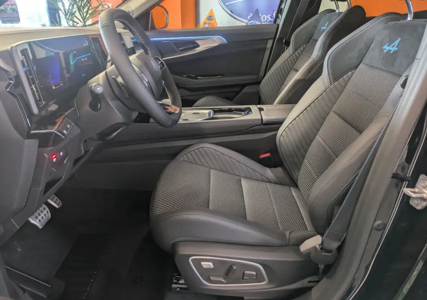 Intérieur côté conducteur du Renault Austral noir, sièges sport avec logo Alpine bleu et tableau de bord numérique.