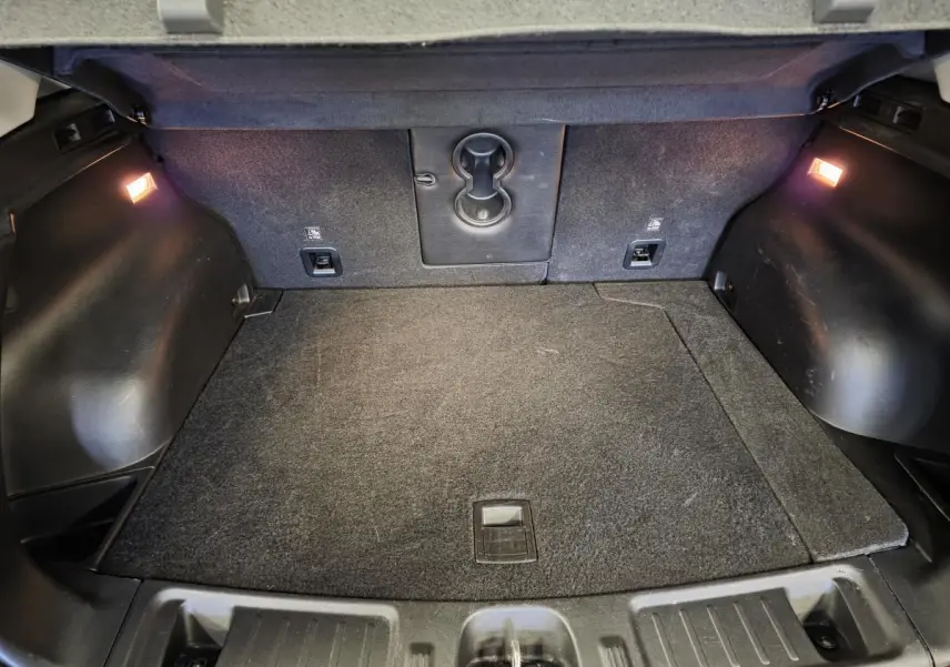 Coffre spacieux du Jeep Compass Trailhawk 2024 noir, avec éclairage intérieur et tapis de coffre gris.