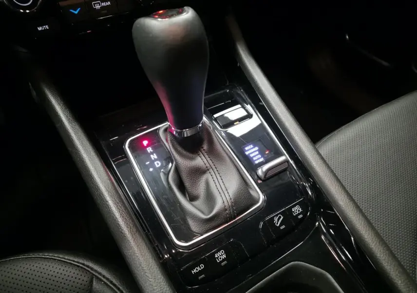 Gros plan sur la console centrale noire du Jeep Compass 2024 avec levier de vitesses automatique et commandes 4WD visibles.