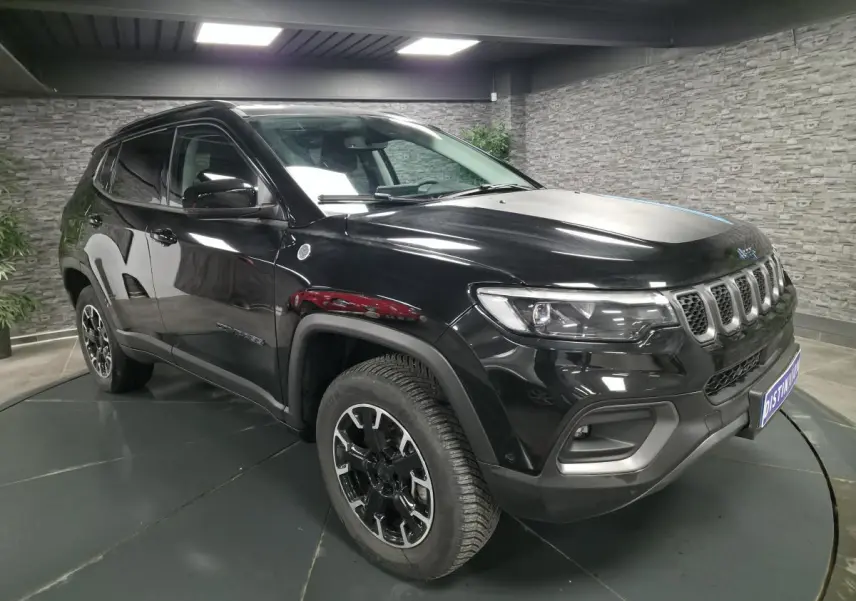 Jeep Compass Trailhawk noir en 3/4 avant droit avec jantes alliage et signature lumineuse LED visible.