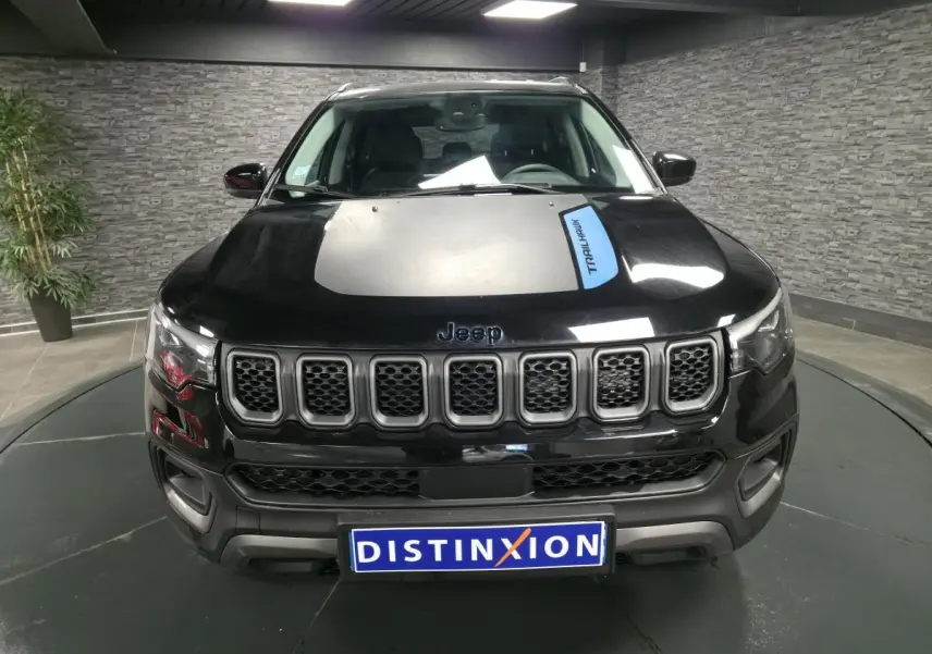 Vue de face d'un Jeep Compass Trailhawk noir avec calandre distinctive et sticker Trailhawk sur le capot.