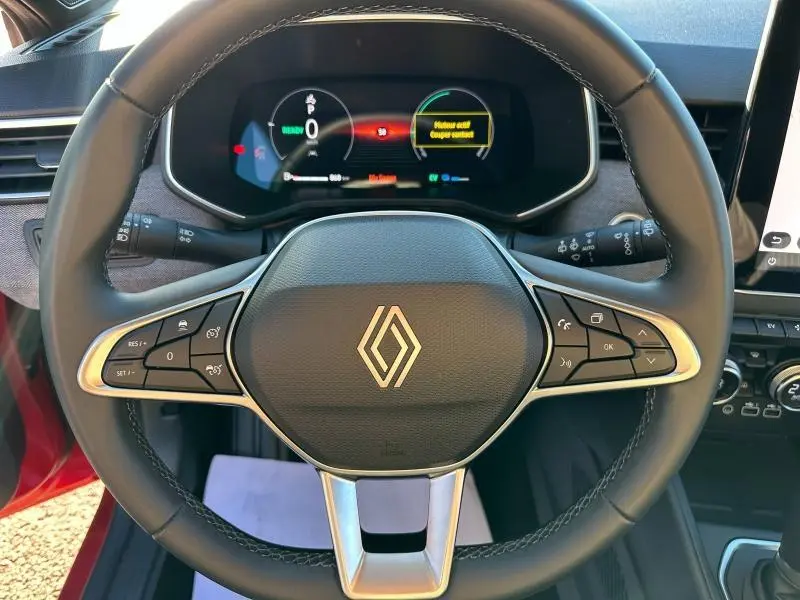Vue rapprochée du volant multifonction de la Renault Clio 1.6 E-Tech 145ch rouge Flamme avec tableau de bord numérique.