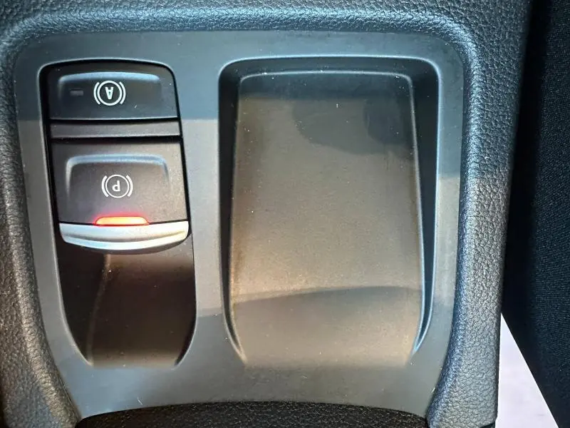 Gros plan sur les commandes de frein à main électrique et auto hold dans la console centrale de la Renault Clio 1.6 E-Tech Rouge Flamme.