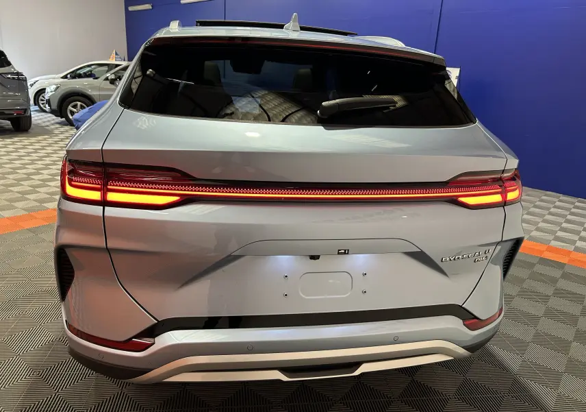 Vue arrière du BYD SEAL U hybride rechargeable en TIAN QING METAL avec feux LED allumés dans un showroom.
