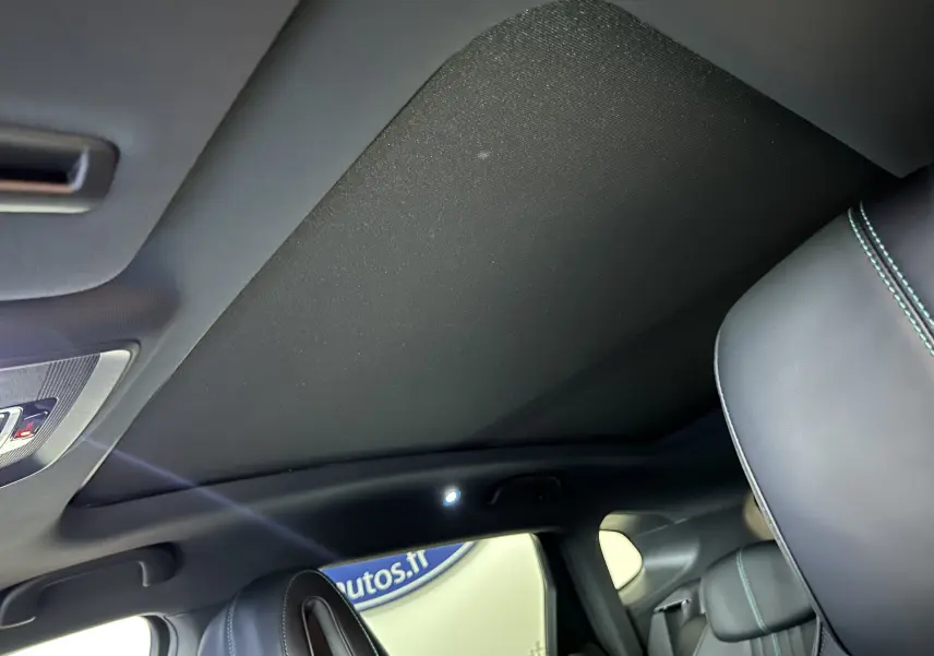 Vue intérieure du toit ouvrant fermé et des sièges en cuir noir avec surpiqûres bleues du BYD SEAL U 2025.