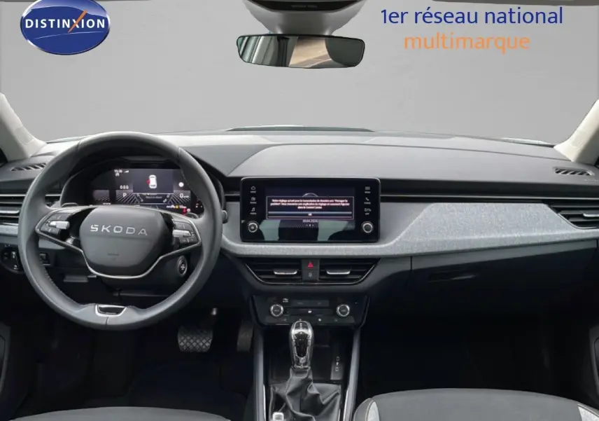 Vue intérieure frontale du tableau de bord et volant SKODA KAMIQ avec écran tactile central et finition tissu noir.