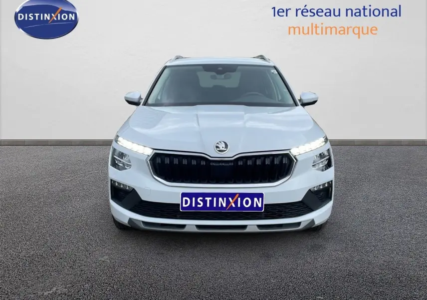 Vue frontale d'un Skoda Kamiq blanc glacier 2025 avec calandre noire et feux LED allumés sur fond neutre.