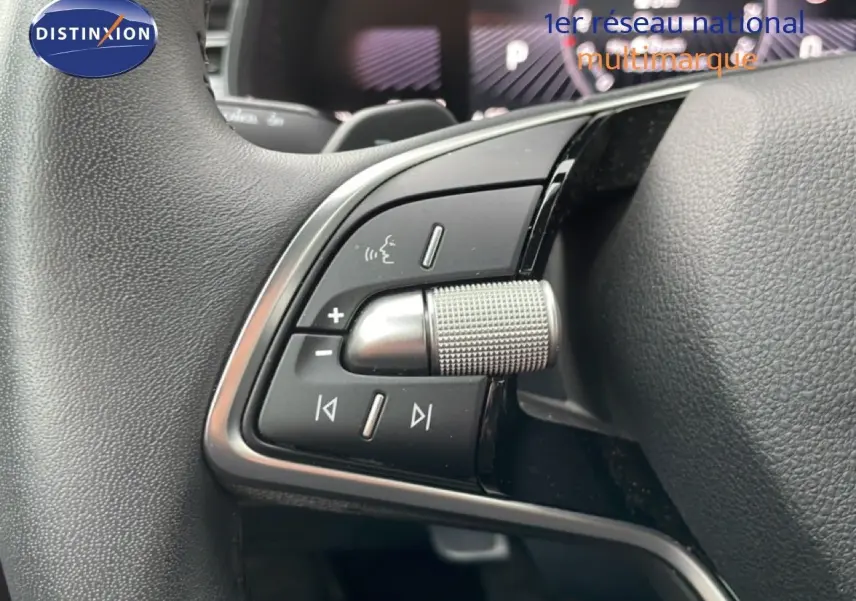 Gros plan sur les commandes multifonctions en métal brossé du volant d’un Skoda Kamiq blanc glacier 2025.