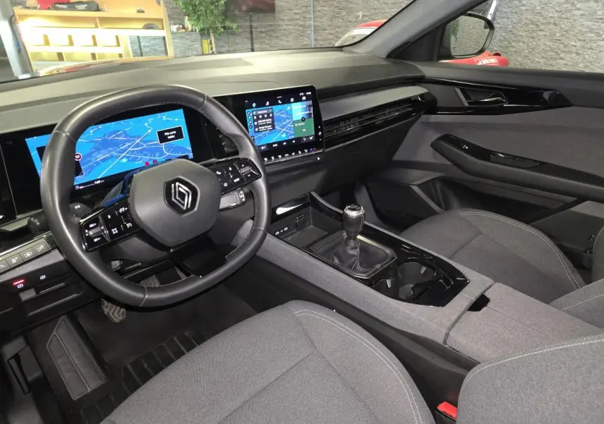Intérieur avant droit du Renault Austral gris, volant multifonction, écran tactile et boîte manuelle visible.